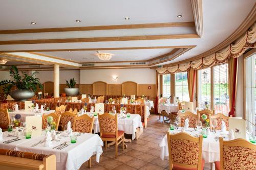 uma sala de jantar com mesas e cadeiras brancas em Vital Sporthotel Kristall em Finkenberg
