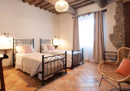 Un dormitorio con dos camas y una silla y una ventana. en Villa La Ginestra con piscina privata, en Umbertide