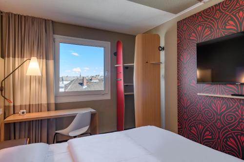 um quarto de hotel com uma cama, uma secretária e uma janela em T H E Darmstadt em Darmstadt