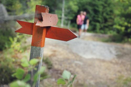a wooden sign on a trail with people walking on a path at Stiftsgården Vårdnäs Hotell in Brokind