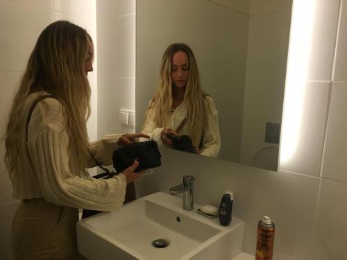 une femme prenant une photo d'elle-même dans un miroir de bain dans l'établissement Onefam Ribeira, à Porto