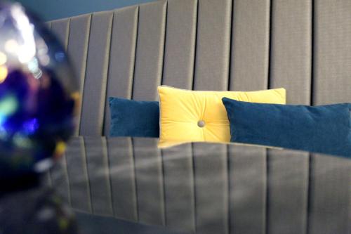 a bed with a yellow pillow and blue pillows at NOX Waterloo in London