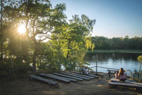 a group of people sitting on a bench by a lake at Stiftsgården Vårdnäs Hotell in Brokind