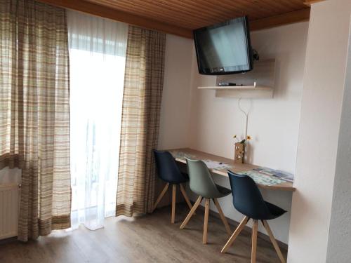 une salle à manger avec une table, des chaises et une télévision dans l'établissement Bauernhof Landhaus Hofer, à Annenheim