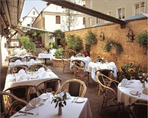 un restaurant avec des tables et des chaises blanches dans une cour dans l'établissement Hotel Eberbacher Hof, à Biberach an der Riß