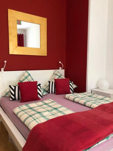 a bedroom with two beds with red walls and a mirror at Apartment Alaune in Dresden