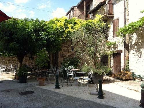 a patio with tables and chairs and a building at Auberge du Puits in Souillac