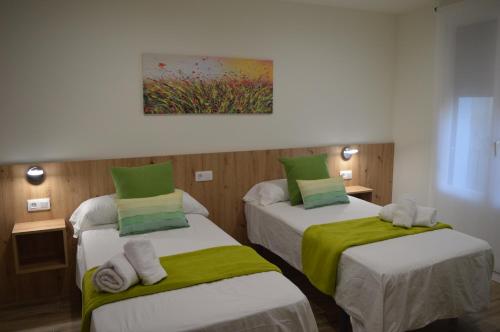 Habitación con 2 camas y sábanas verdes y blancas. en Casa Del Carmen II - Parking incluido, en Tudela