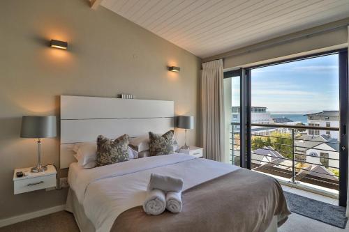 een slaapkamer met een groot bed en een groot raam bij Whale Coast All-Suite-Hotel - DCC Hotel Group in Hermanus