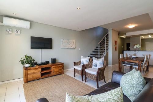 a living room with a couch and a tv and a table at Whale Coast All-Suite-Hotel - DCC Hotel Group in Hermanus