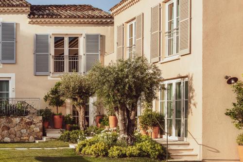 a house with a tree in the front yard at Hotel Lou Pinet in Saint-Tropez