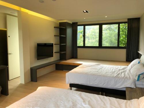a bedroom with two beds and a flat screen tv at Ming Yueju in Guoxing