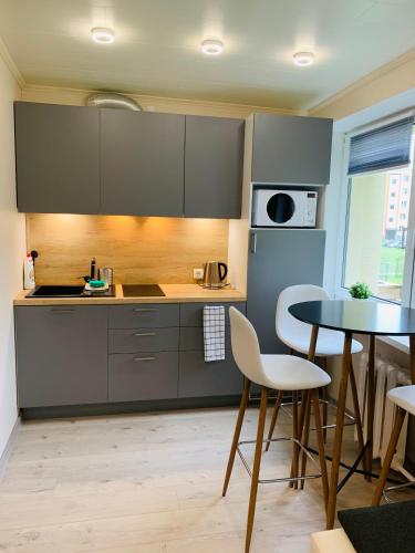 uma cozinha com armários cinzentos, uma mesa e cadeiras em Sepa Apartment em Valga