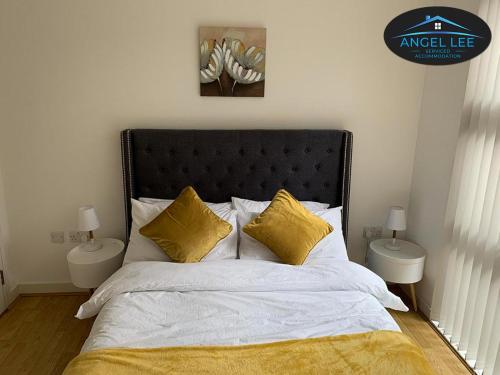 a bedroom with a large bed with yellow pillows at Angel Lee Serviced Accommodation, Diego London, 1 Bedroom Apartment in London