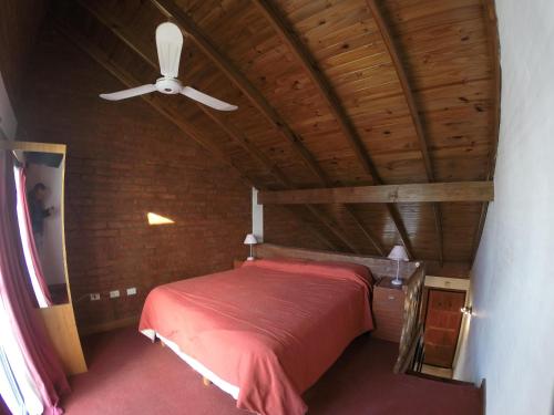 - une chambre avec un lit rouge et un ventilateur de plafond dans l'établissement Arenas Blancas, à Puerto Madryn