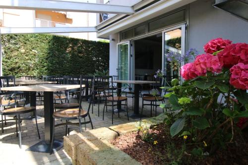 a patio with tables and chairs and pink roses at Eraclea Palace Appartements in Eraclea Mare