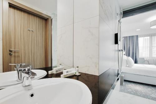 a white bathroom with a sink and a shower at Golden Tulip Krakow Kazimierz in Krakow
