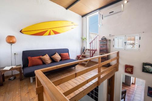 ein Wohnzimmer mit einem blauen Sofa und einem Surfbrett an der Wand in der Unterkunft Casa Drago - Villa Perenquén in Guía de Isora