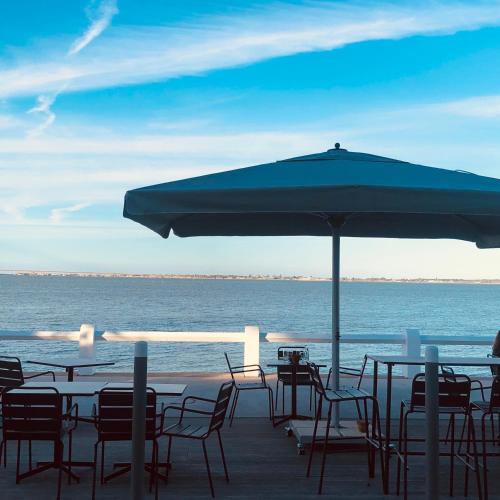 a group of tables and chairs under an umbrella on the beach at Le Homard Bleu in Saint-Trojan-les-Bains