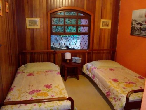 2 camas en una habitación con ventana en Casa - Flores Encantadas, en Campos do Jordão