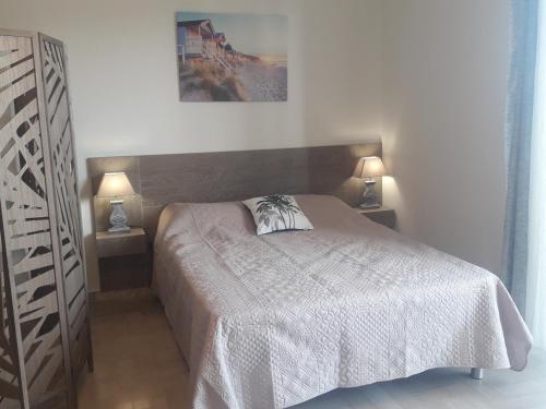 - une chambre avec un lit et 2 lampes sur 2 tables dans l'établissement BRILOC Appartement Route des îles Sanguinaires, à Ajaccio