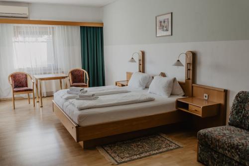 a hotel room with a large bed and a chair at Georgshof in Podersdorf am See