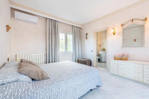a white bedroom with a bed and a mirror at Villa Son Ferrer in Santa Ponsa