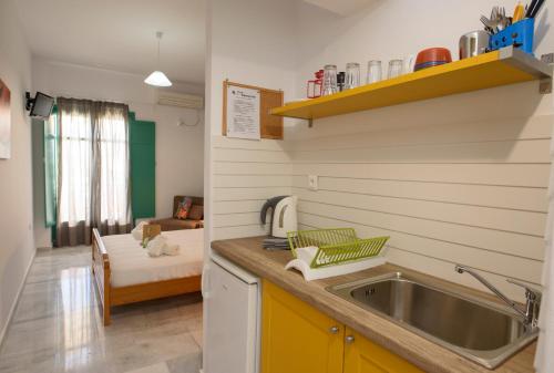 een keuken met een wastafel en een woonkamer bij Porto Katapola Pension in Katápola