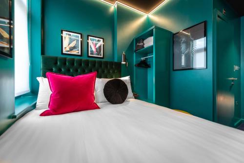 a green bedroom with a large bed with red pillows at Hux Hotel, Kensington in London