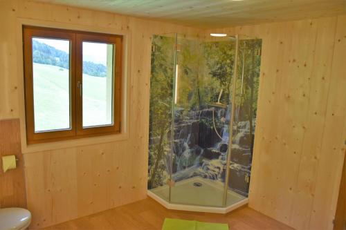a glass shower in a wooden room with a window at Ferienhaus Brittenberg in Schwarzenberg im Bregenzerwald