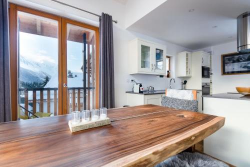 - une cuisine avec une table en bois et une vue sur la montagne dans l'établissement Petit Yeti Chalet, à Chamonix-Mont-Blanc