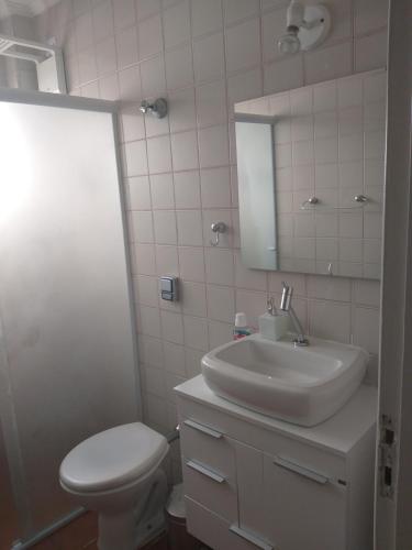 ein Badezimmer mit einem Waschbecken, einem WC und einem Spiegel in der Unterkunft Frente para o mar - vista espetacular de todos os cômodos in Praia Grande
