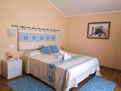 Schlafzimmer mit einem Bett mit blauer und weißer Bettwäsche in der Unterkunft Le Orchidee in Bosa