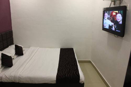 a bedroom with a bed with a tv on the wall at Hotel Fortune in Mumbai