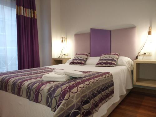 1 dormitorio con 1 cama grande con toques morados en Descanso do Sar en Santiago de Compostela