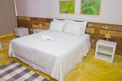 um quarto com uma cama grande e uma colcha branca em Pousada Parador da Figueira em Lagoa da Prata