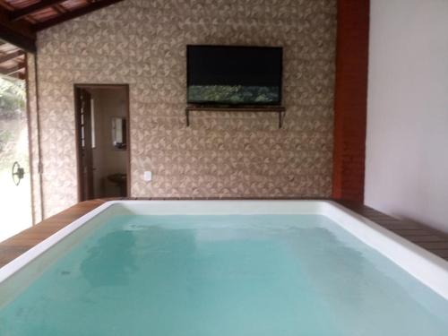 a swimming pool in a room with a tv on the wall at Eco Chalés Águas Claras in Lumiar