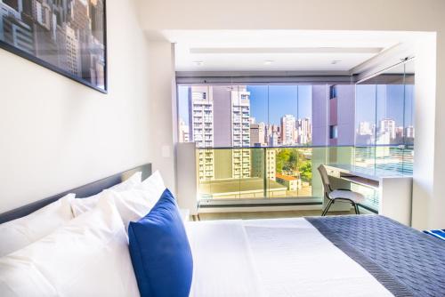 a bedroom with a bed and a view of a city at 360 Perdizes in Sao Paulo