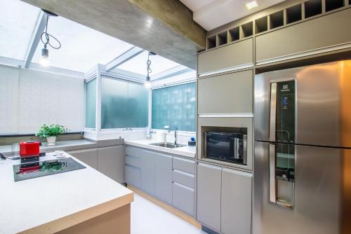 a large kitchen with white cabinets and a refrigerator at 360 Perdizes in Sao Paulo