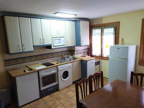 a kitchen with a stove and a dishwasher and a table at APARTAMENTO Txapatera EN IZABA-ISABA in Isaba