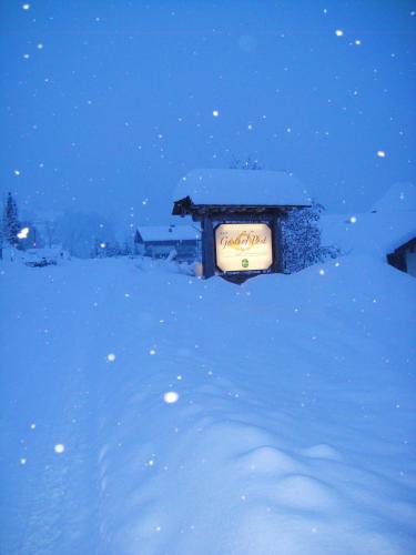 a sign is covered in snow at night at Gasthof Post in Rennweg
