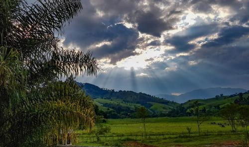 a cloudy sky with the sun shining in a field at Pousada Rota dos Pássaros in São Bento do Sapucaí
