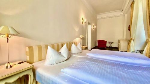 a hotel room with a large white bed with white pillows at Hotel Graf von Mansfeld in Lutherstadt Eisleben
