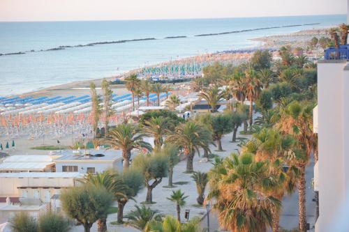 una vista aerea di una spiaggia con palme e ombrelloni di Hotel Altis a San Benedetto del Tronto