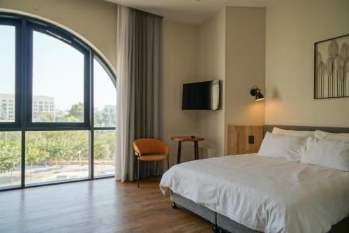 Cette chambre comprend un lit et une grande fenêtre. dans l'établissement Apartique Hotel, à Jérusalem