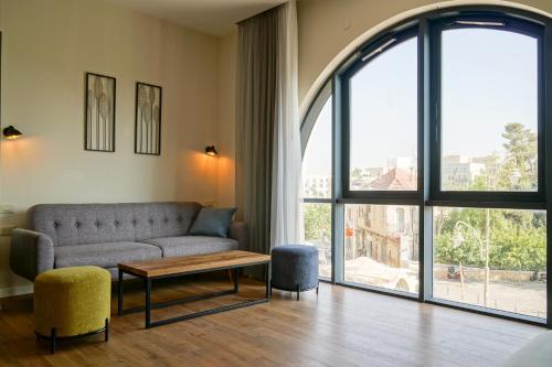 a living room with a couch and a large window at Apartique Hotel in Jerusalem