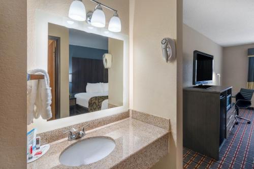 a bathroom with a sink and a large mirror at Baymont by Wyndham Tupelo in Tupelo