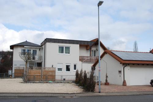 a white house with a fence and a pole at Ferienwohnungen Schäfer in Obersulm
