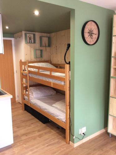 Ce lit se trouve dans un dortoir doté de 2 lits superposés et d'une horloge murale. dans l'établissement Les Obiones, vue latérale mer, Fort Mahon Plage, magnifique studio cabine 4p, avec balcon , parking privé gratuit, wifi, classé 2 étoiles, exposition plein sud en Baie de Somme, à Fort-Mahon-Plage
