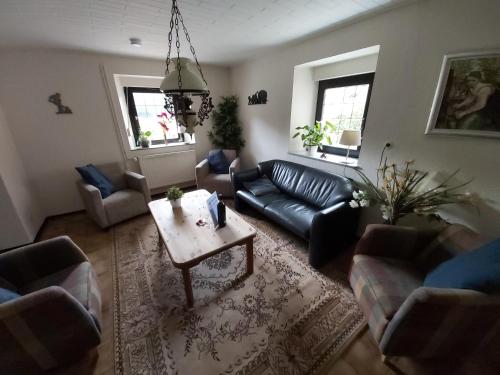 a living room with a black leather couch and a table at die rote Ente in Mürlenbach